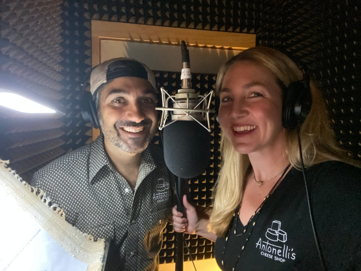 Two adults in a recording studio with headsets behind a microphone