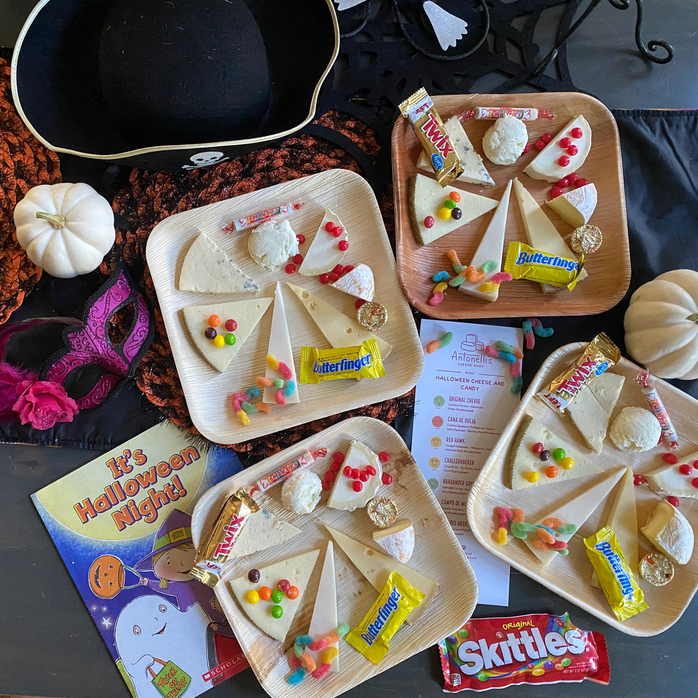 four cheese plates with 7 slices of cheese and multiple different types of halloween candy including skittles.