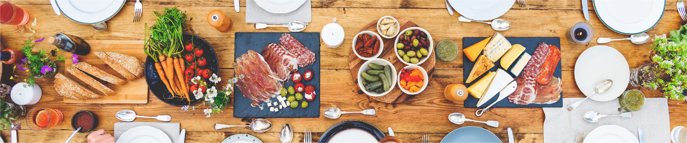 Shop Local.  Image of cheese and charcuterie on a dining table with vegetables and bread
