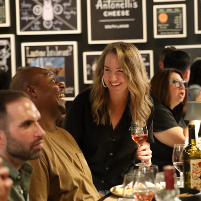 People sitting at a bar with drinks, smiling and engaged in conversation.