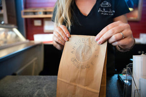 IMage of cheesemonger holding an Antonelli's cheese bag.