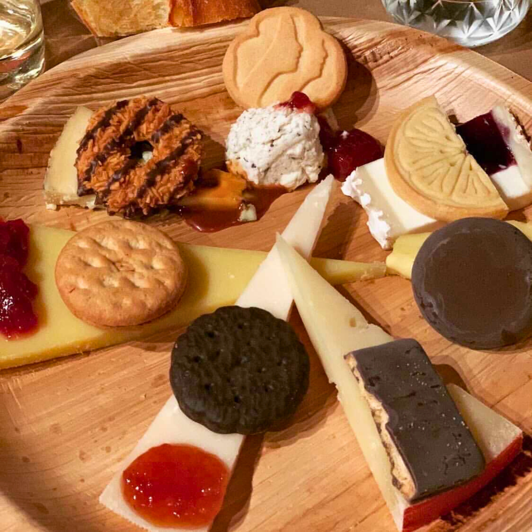 Assorted cookies and desserts on a wooden board with a glass of water in the background.