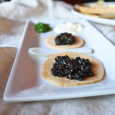 Caviar on crackers on a white plate with a blurred background