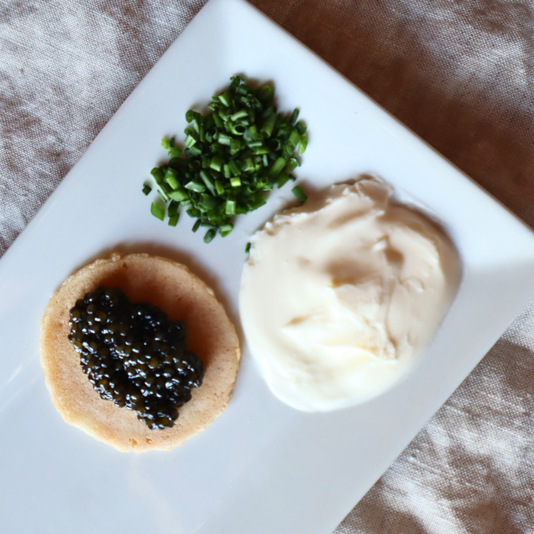Three small round appetizers with different toppings on a white plate.