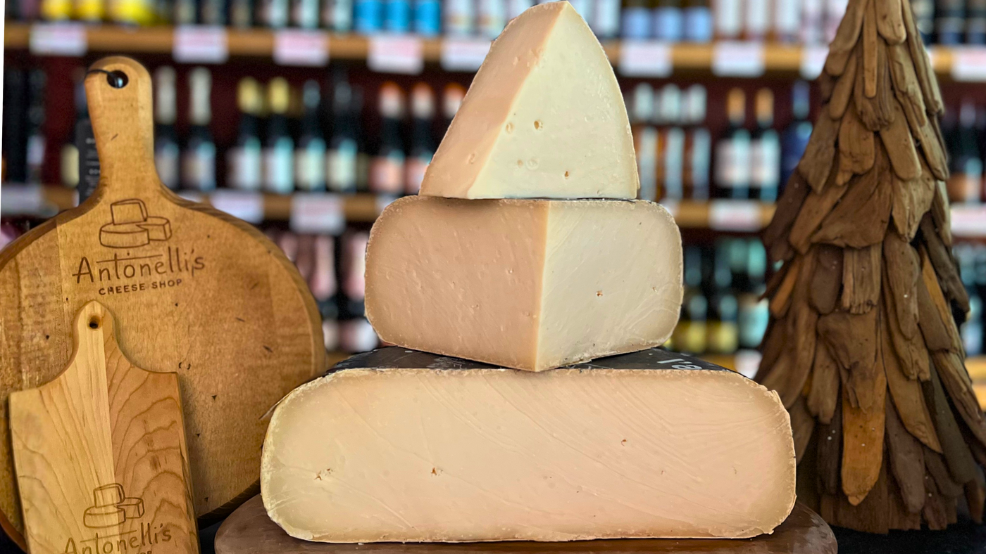 Stack of cheeses with a wooden cutting board and decorative item in a store setting