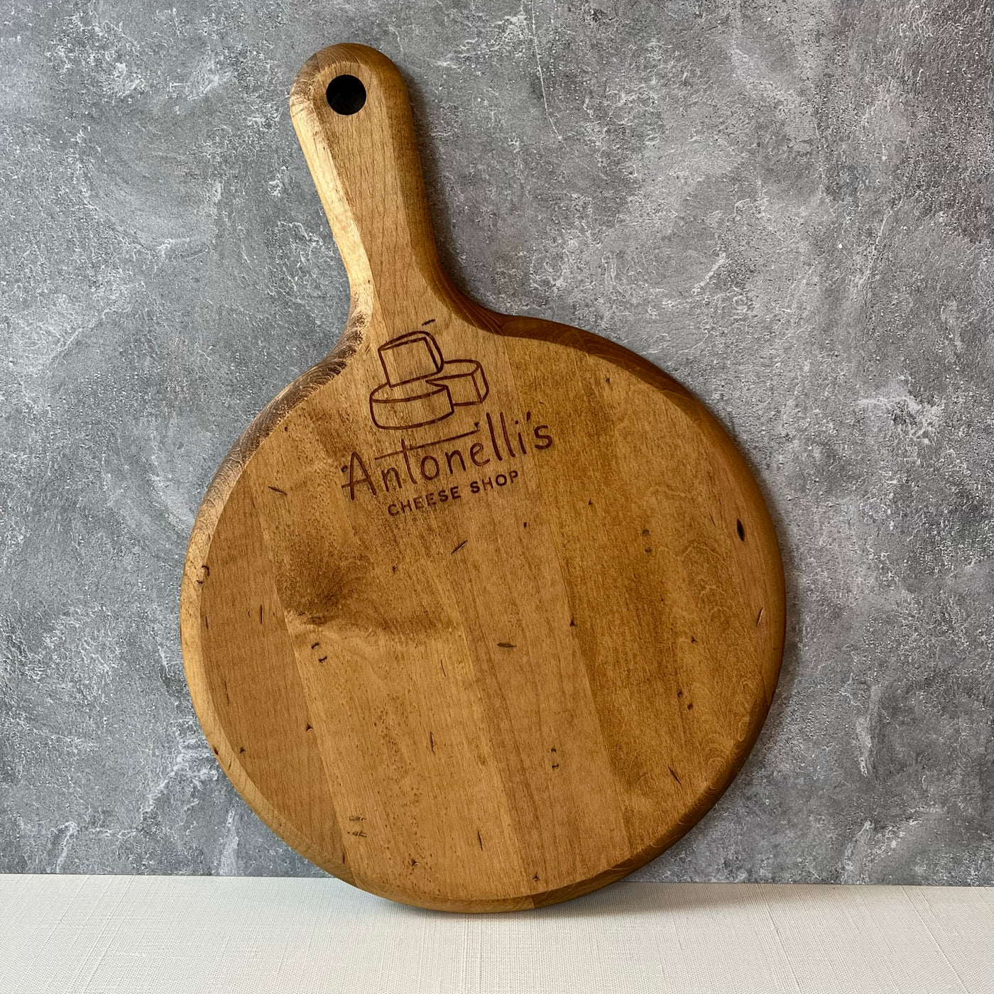 Round cutting board with handle and Antonelli's Cheese logo
