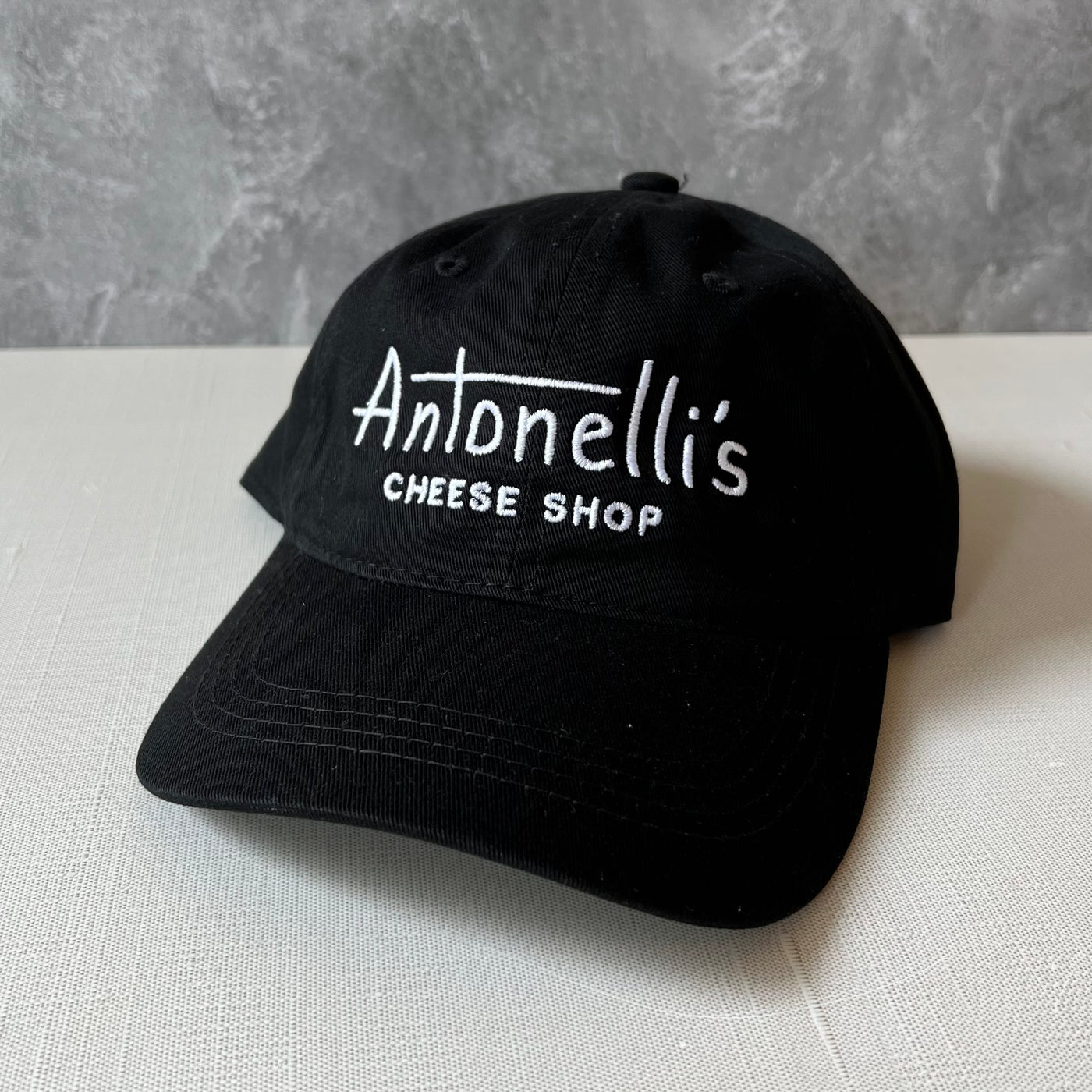 Black hat with "Antonelli's Cheese Shop" logo