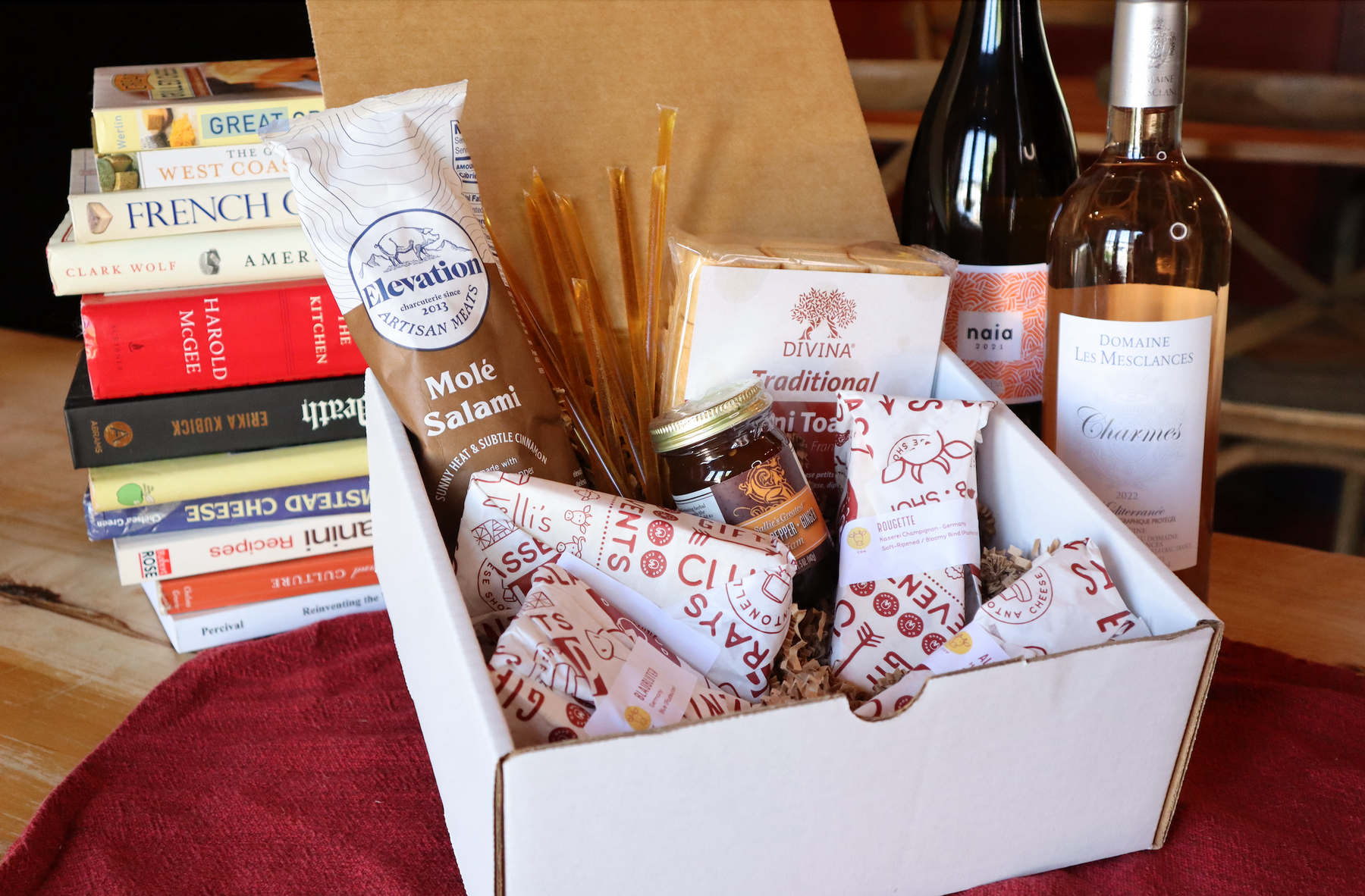 Image of a gift box filled with cheese, jam, meat and honey along with wine