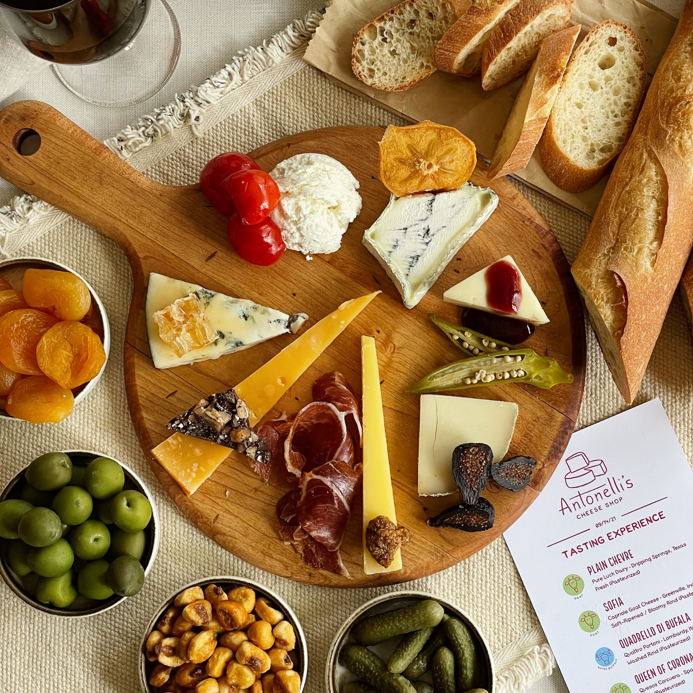 Cheese tasting platter with assorted cheeses, cured meats, bread, olives, corn nuts, figs, and apricots for a charitable event benefiting OLLI.