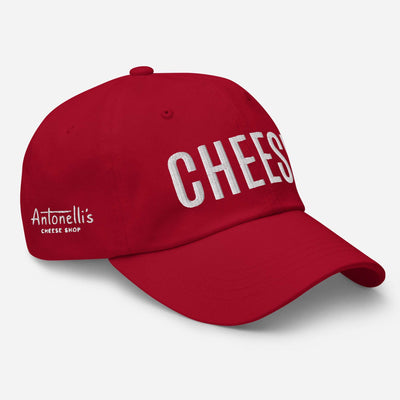 Red dad hat with "CHEESE" text, unstructured low-profile design, curved visor, adjustable strap, embroidered details.