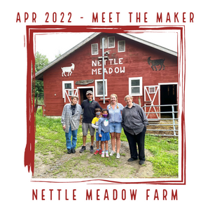 Smiling family standing outside of a red barn