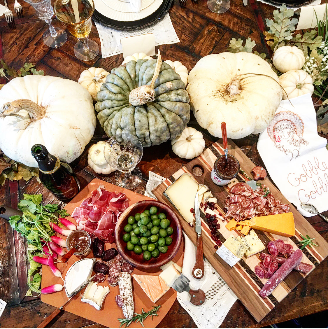 Picture of two cheese plates with wedges of cheese, meat, olives and pumpkins for festive thanksgiving