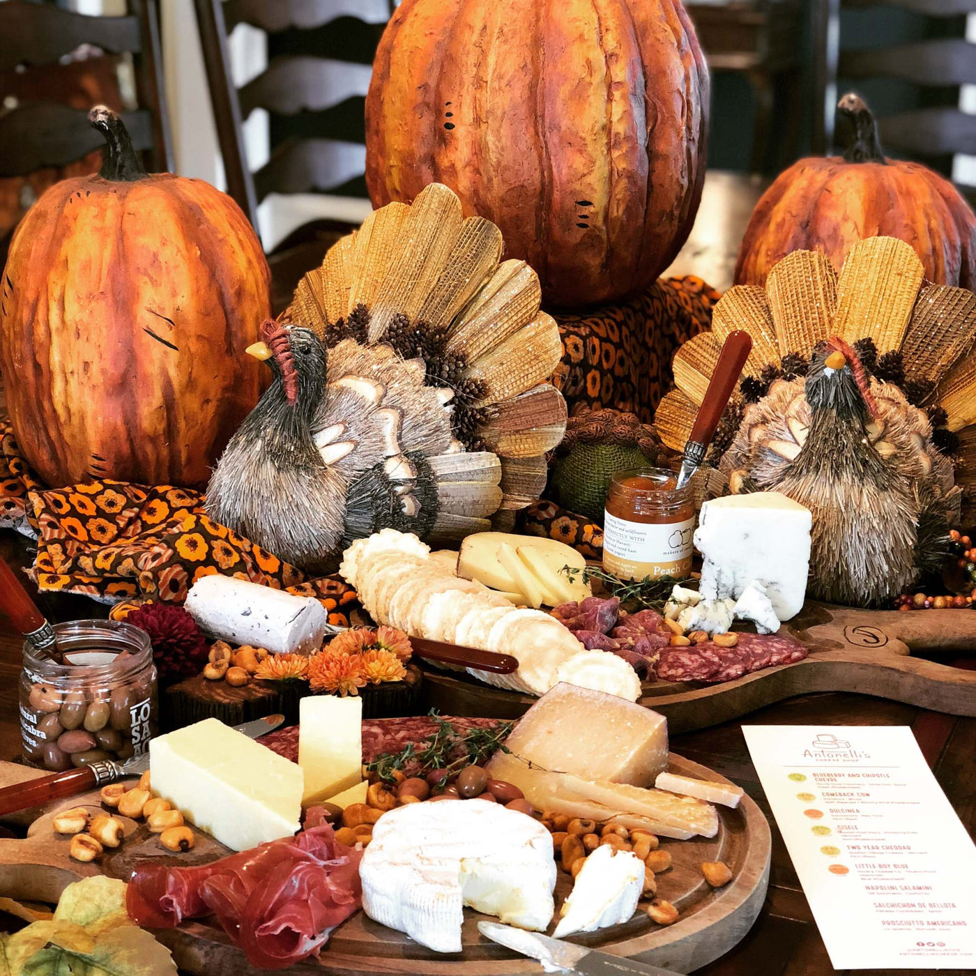 Picture of two cheese plates with wedges of cheese, meat, olives and pumpkins for festive thanksgiving