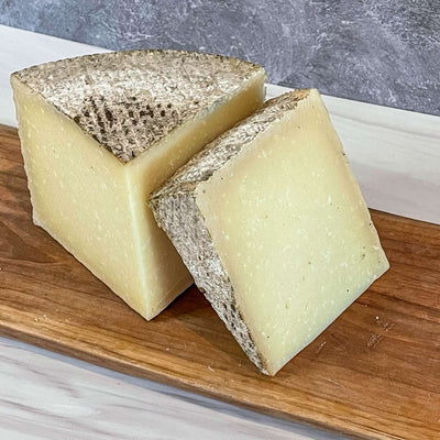1605 Manchego cheese with unwaxed rind on wooden board, Essex St. Cheese.
