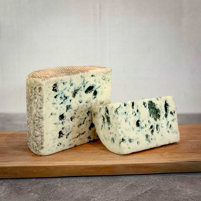 FOURME D'AMBERT blue cheese by Herve Mons from France, creamy and smooth texture, on a wooden board.