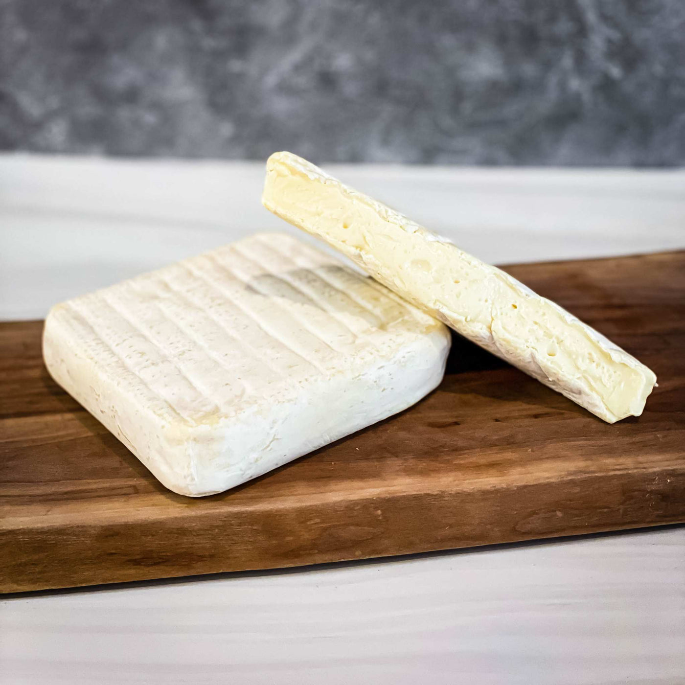 ROBIOLA BOSINA Alta Langa soft-ripened cheese made from sheep and cow milk on wooden board.