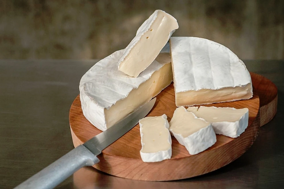 Moses Sleeper cheese from Jasper Hill Farm, Vermont, soft-ripened with white rind on wooden board.